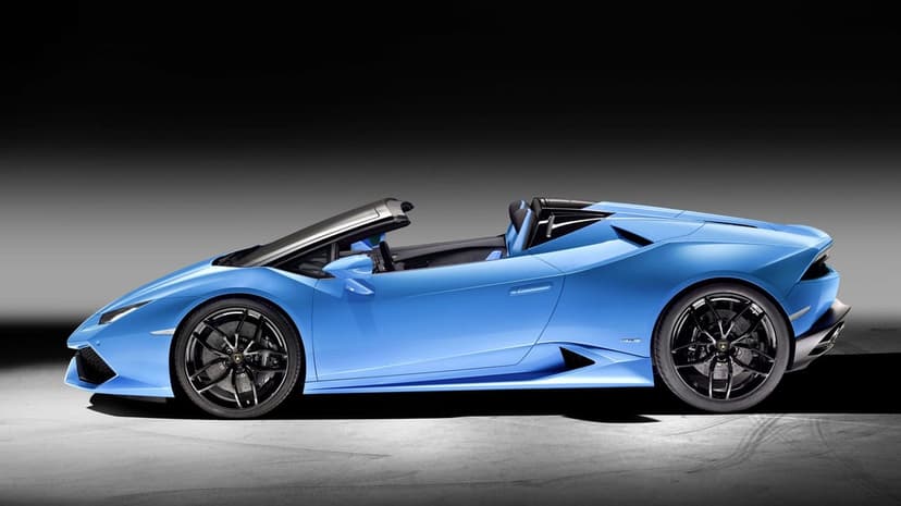 Light blue Lamborghini Huracán Spyder profile view in a dark studio with dramatic lighting and black wheels.