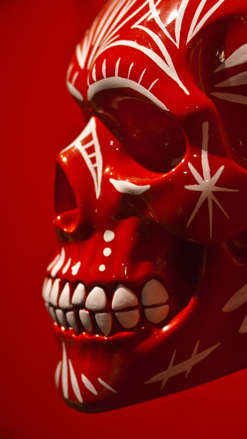 Red skull with white floral patterns and ornate filigree carvings centered on a solid crimson background.