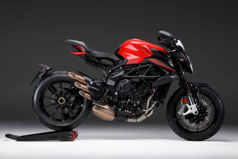 Red and black MV Agusta Dragster sportbike with triple bronze exhausts on a paddock stand in a studio.