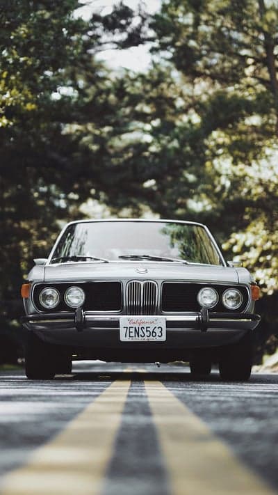 Retro Silver BMW Coupe On Wooded Road Phone Background