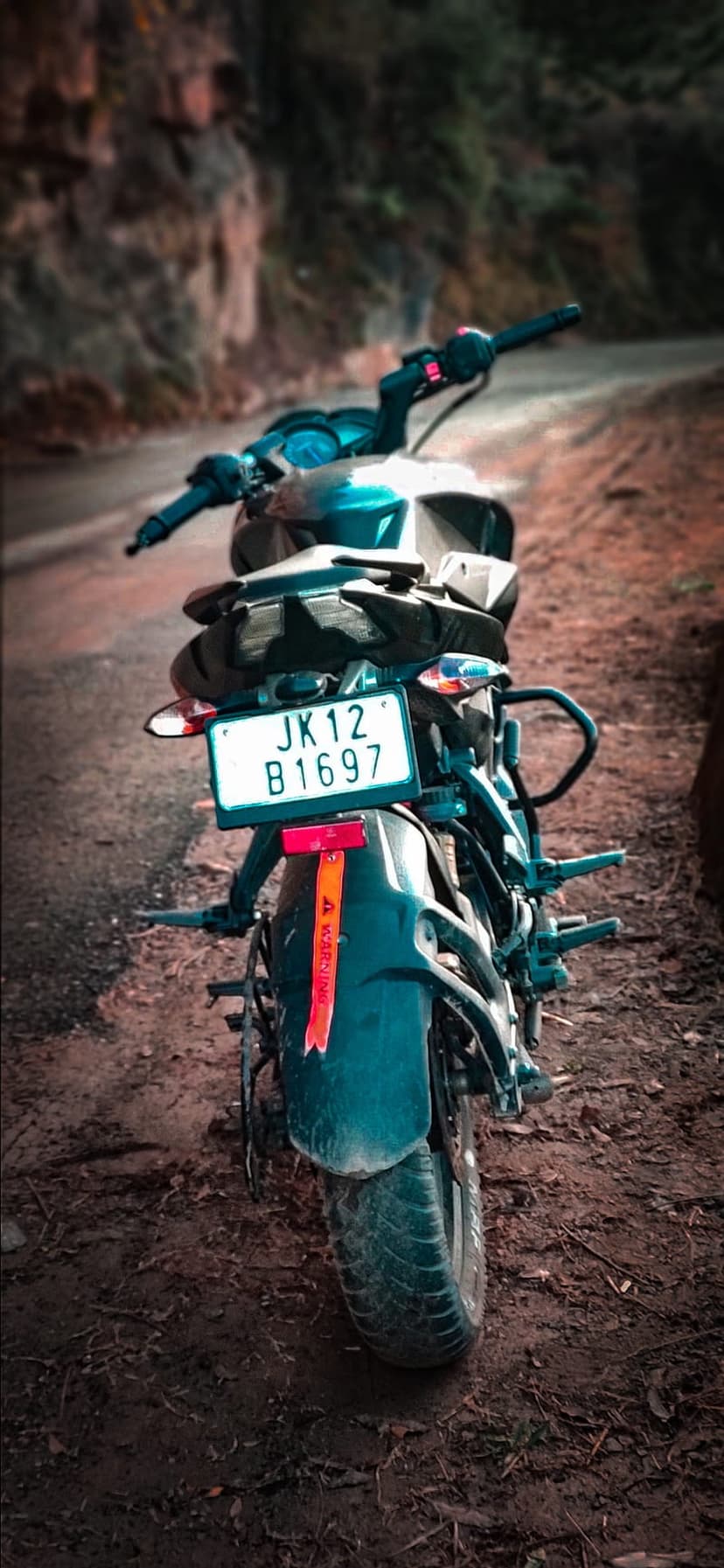 Black and blue sport motorcycle parked on a dusty dirt road with a blurred mountain vista in the distance.