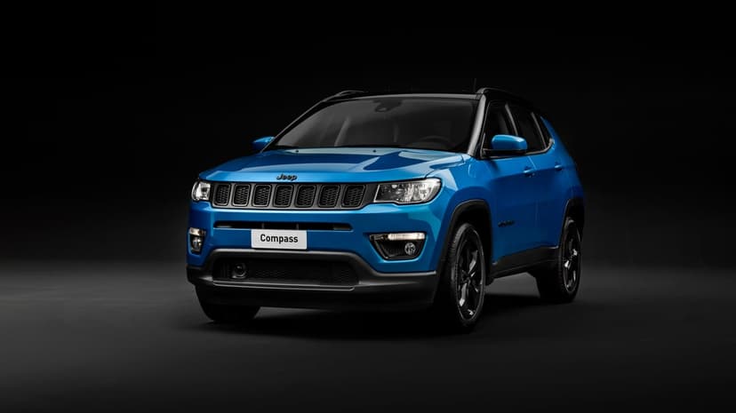 Blue Jeep Compass SUV parked in a dark studio with bright highlights on the hood and metallic body.