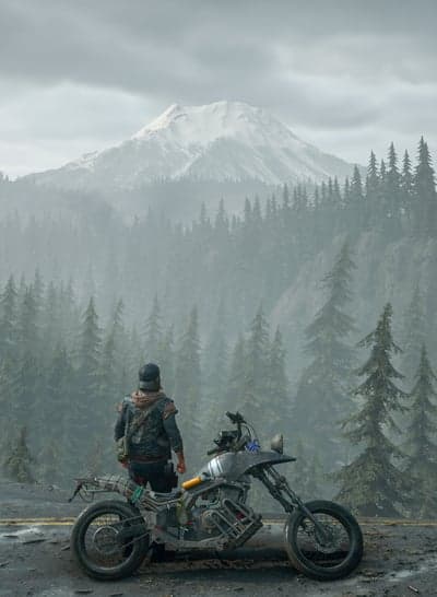 Motorcyclist overlooks misty mountains and evergreen forest