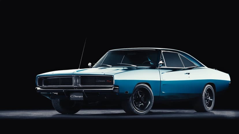 Teal 1969 Dodge Charger muscle car with black wheels and chrome trim against a dark studio background.