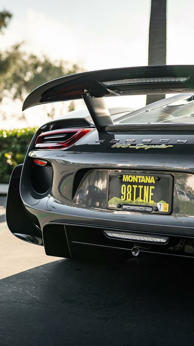 Porsche 918 Spyder rear view with a black paint finish, carbon spoiler, and Montana license plate 98TINE.