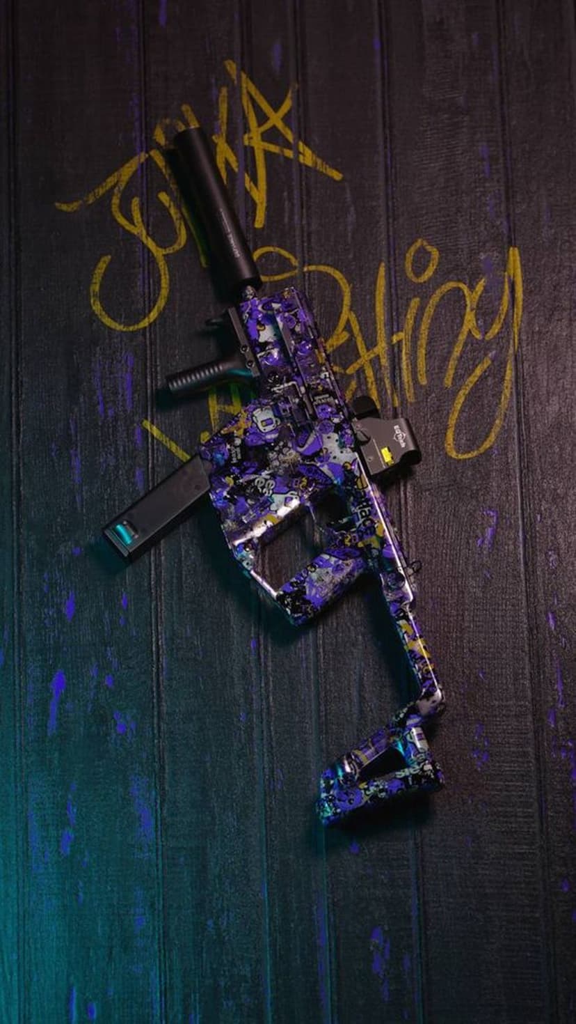 Purple and blue camo submachine gun with a silencer lying on a dark wooden surface with yellow spray paint marks.