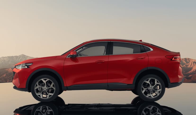Side profile of a vibrant red SUV reflected on a glossy floor with a desert mountain landscape background at sunset.