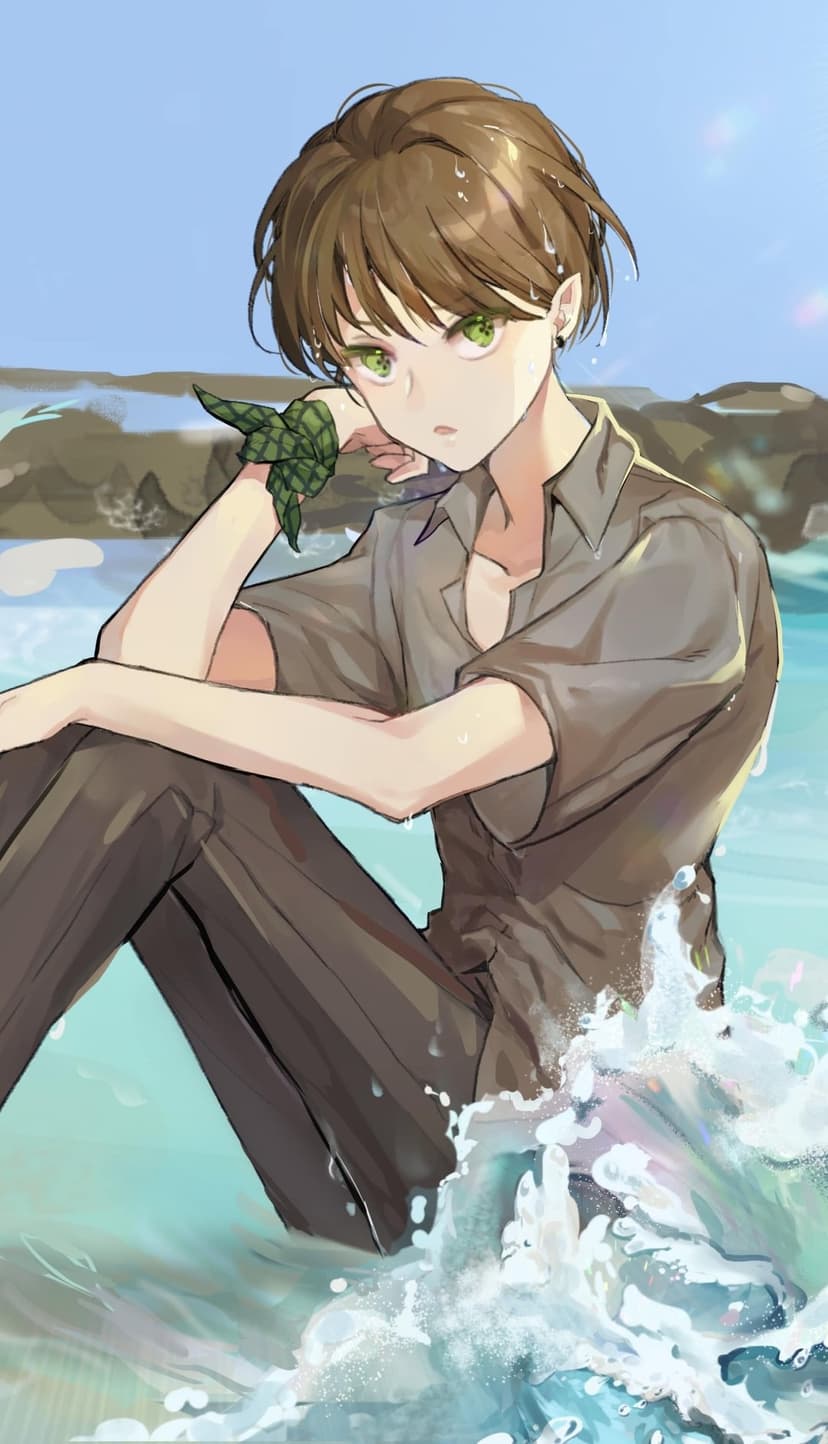 Brown-haired young man with green eyes sits on a beach while ocean waves crash around his gray shirt and dark pants.