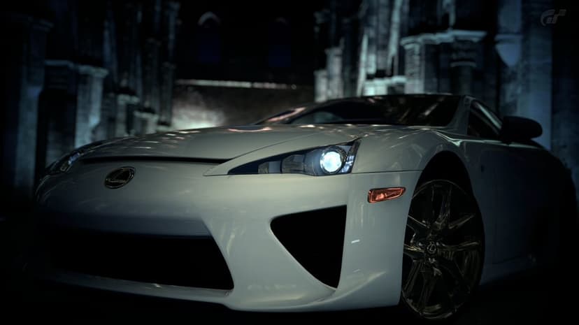 White Lexus LFA supercar with a glowing headlight parked against a dark gothic stone building at night.