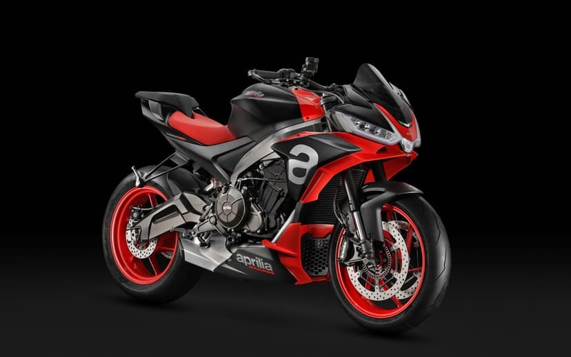 Aprilia Tuono 660 motorcycle with red wheels and seat against a solid black studio background.