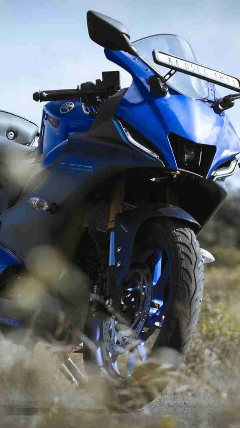 Blue Yamaha R15 sportbike riding through loose dirt with a large cloud of dust trailing behind the rear wheel.