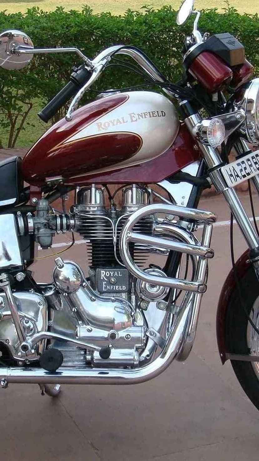 Royal Enfield motorcycle engine with polished chrome cylinders, maroon fuel tank, and silver branding details.