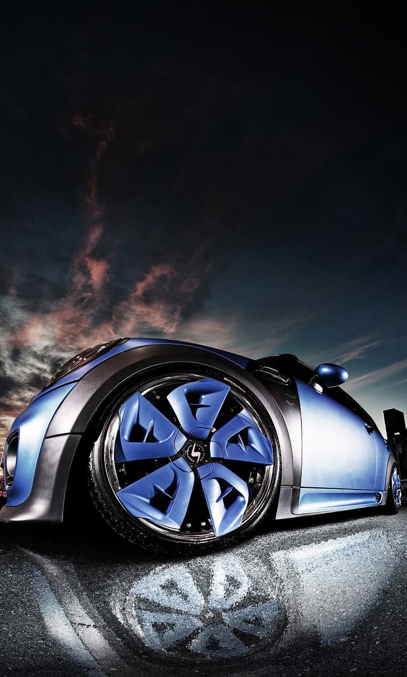 Blue futuristic supercar with glowing cyan wheels parked on a wet street under a dark cloudy sky at twilight.