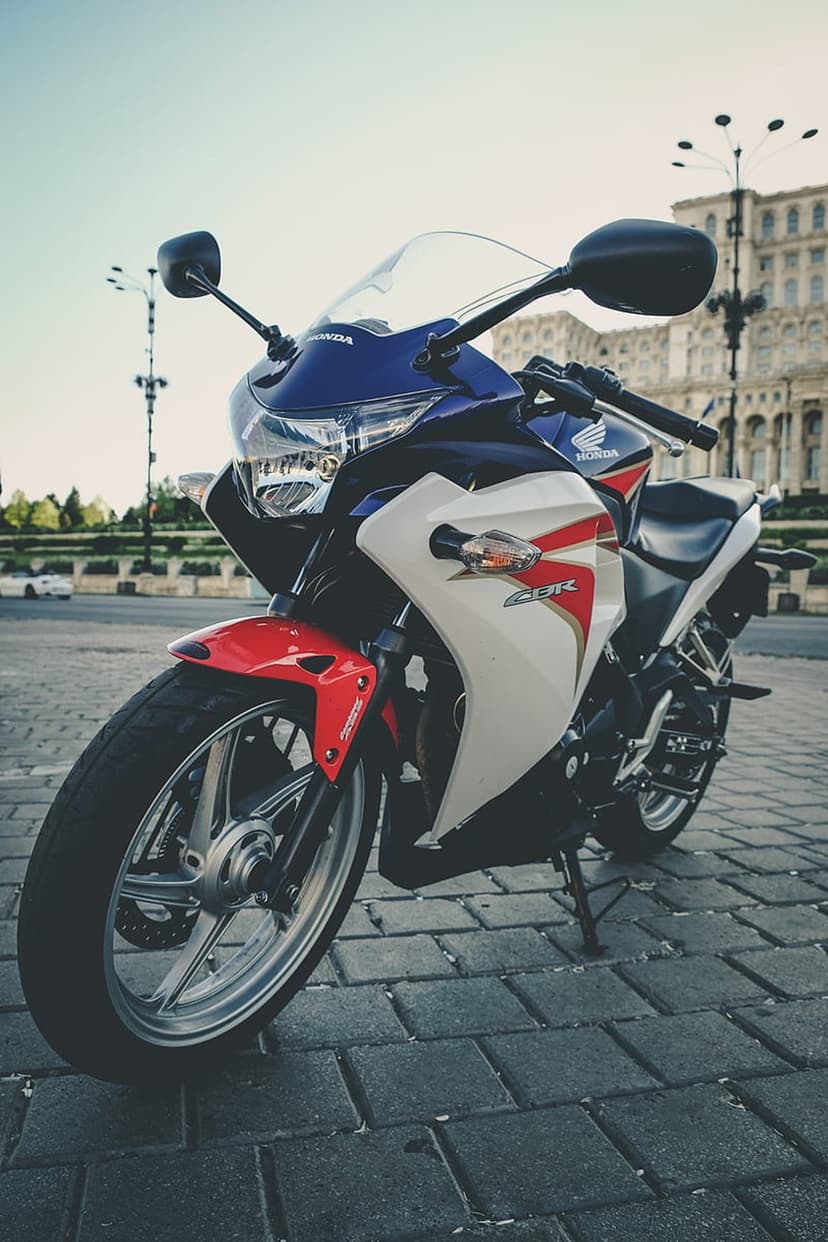 Honda CBR motorcycle in red white and blue parked on urban cobblestones against a grand historic building.