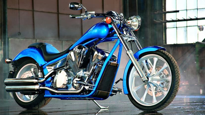 Blue custom cruiser motorcycle with chrome accents parked in a studio with large industrial windows.