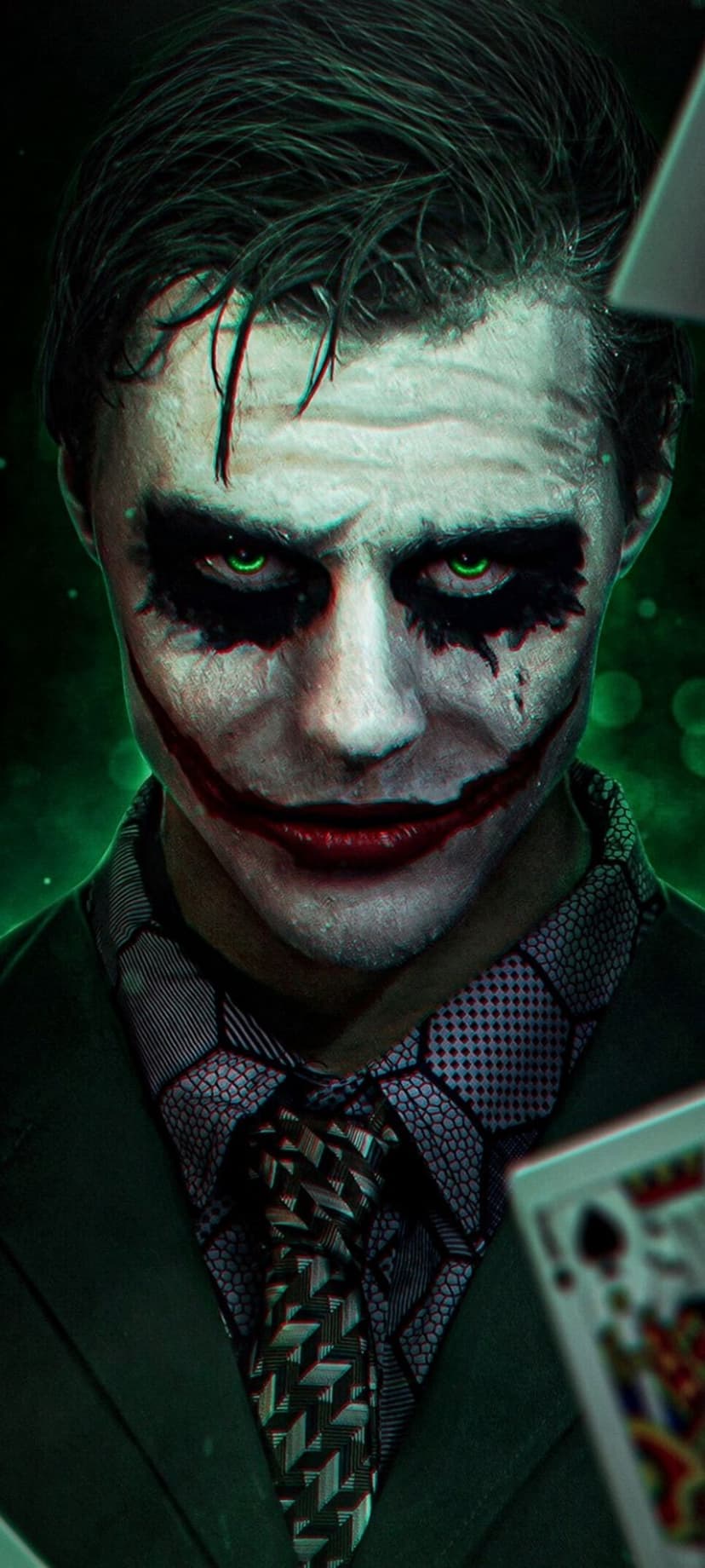 Joker with white face paint and luminous green eyes holds playing cards against a dark, smoky background.