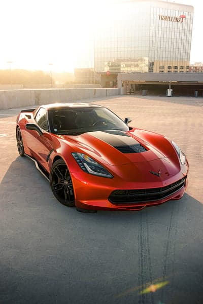 Orange Corvette C7 parked on rooftop at sunset