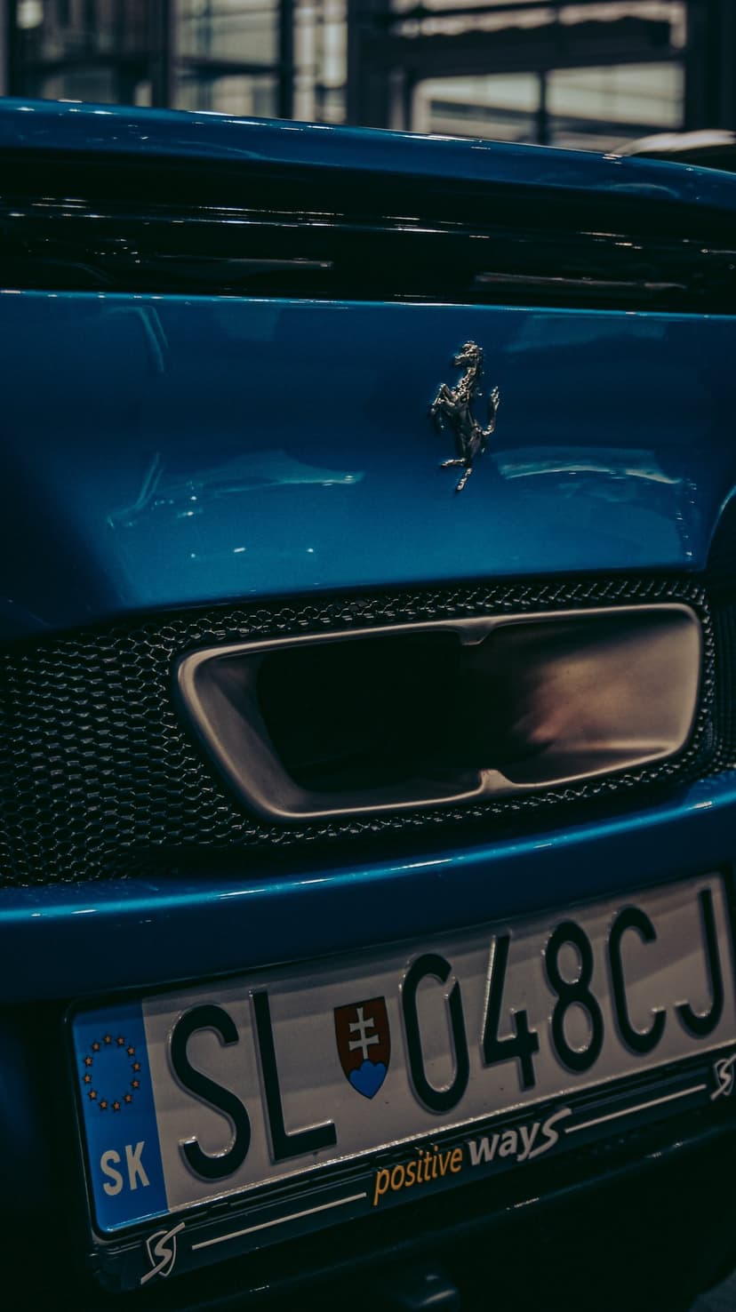 Blue Ferrari rear bumper with a silver prancing horse logo, exhaust vent, and Slovakian license plate SL 048CJ.