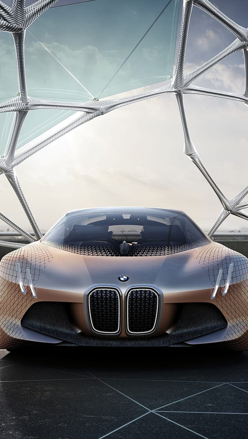 BMW Vision Next 100 concept car featuring a copper metallic finish beneath a complex geometric glass structure.