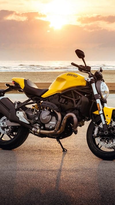 Yellow Ducati Monster motorcycle at sunset beach