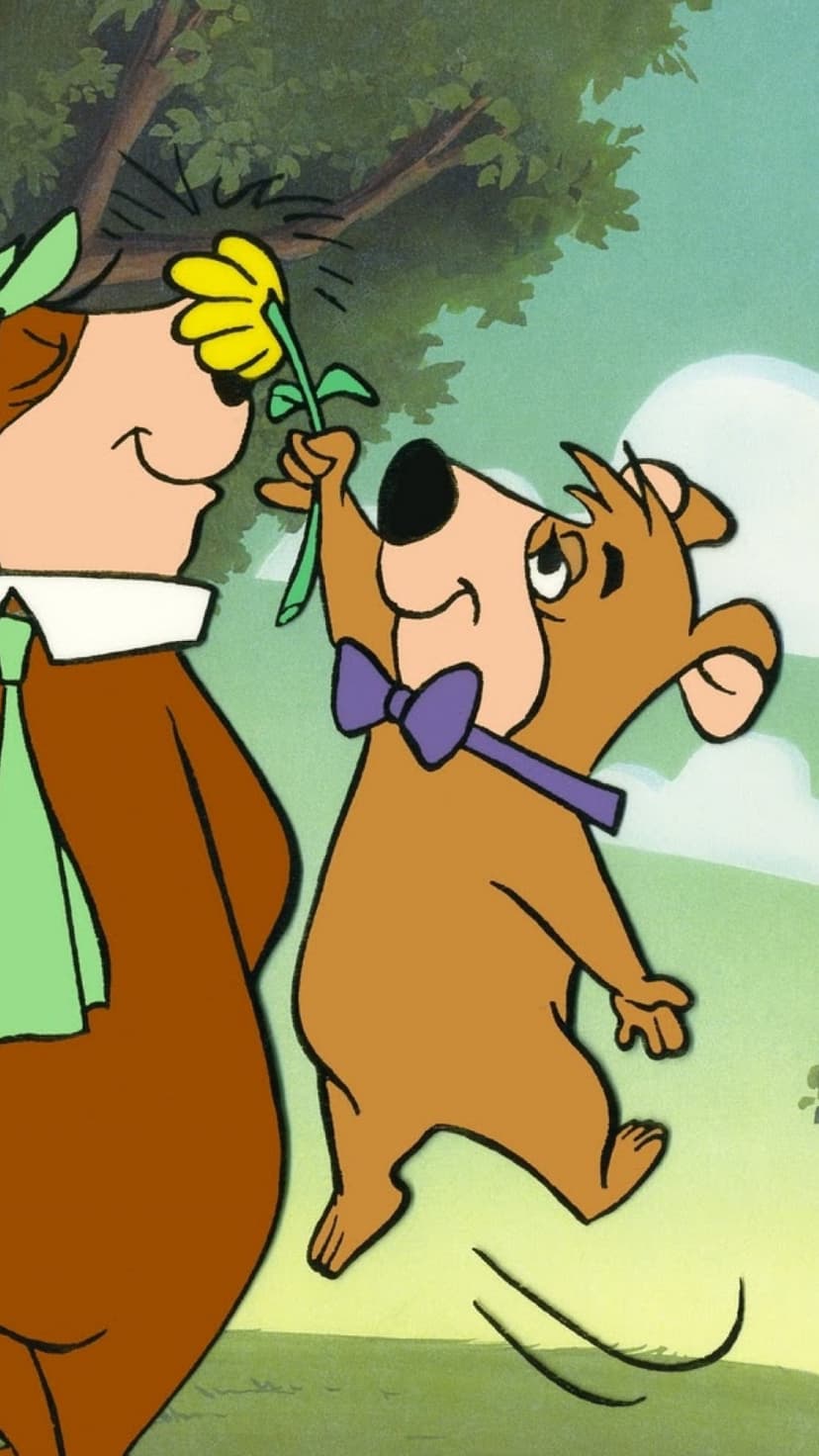 Yogi Bear and Boo Boo stand in a whimsical forest as Boo Boo holds out a bright yellow flower to his friend.