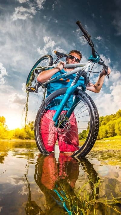 Man Carrying Bicycle Through Water