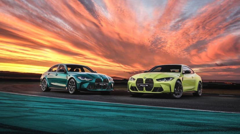 Green and yellow BMW M cars on a race track under a vivid orange and purple sunset sky.