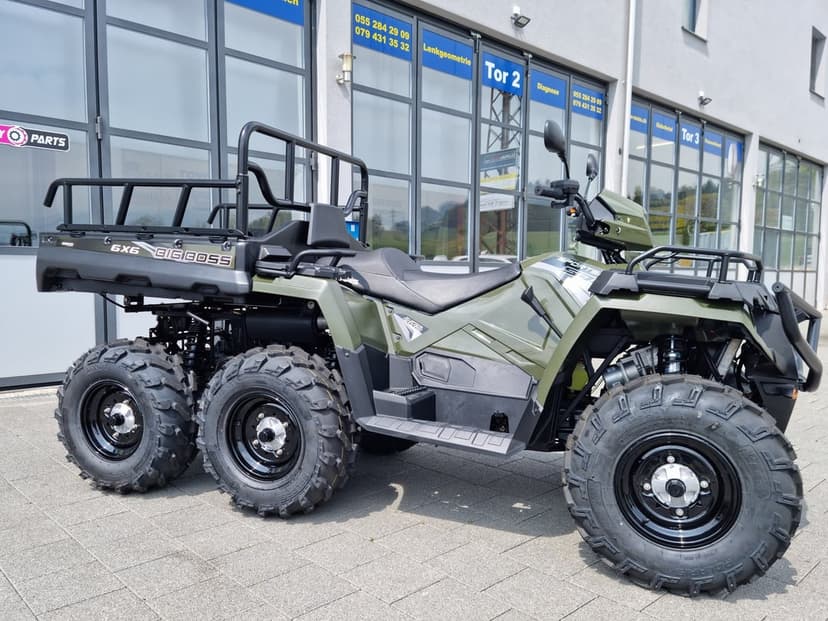 Olive green Polaris Sportsman 6x6 Big Boss ATV with six off-road tires parked on a paved outdoor lot.
