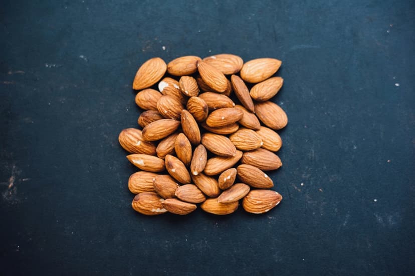 Unshelled almonds piled in a square shape on a dark slate surface highlight natural textures and brown tones.