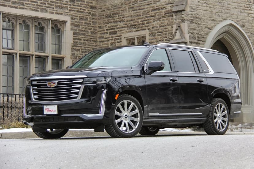 Black Cadillac Escalade luxury SUV parked on a street in front of a grand stone building with arched windows.