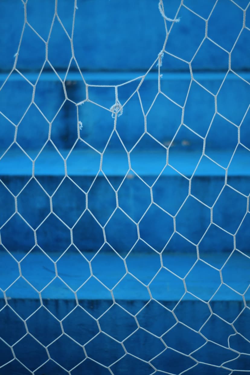 White hexagonal mesh with detailed thread patterns layered over a saturated cobalt blue out-of-focus surface.
