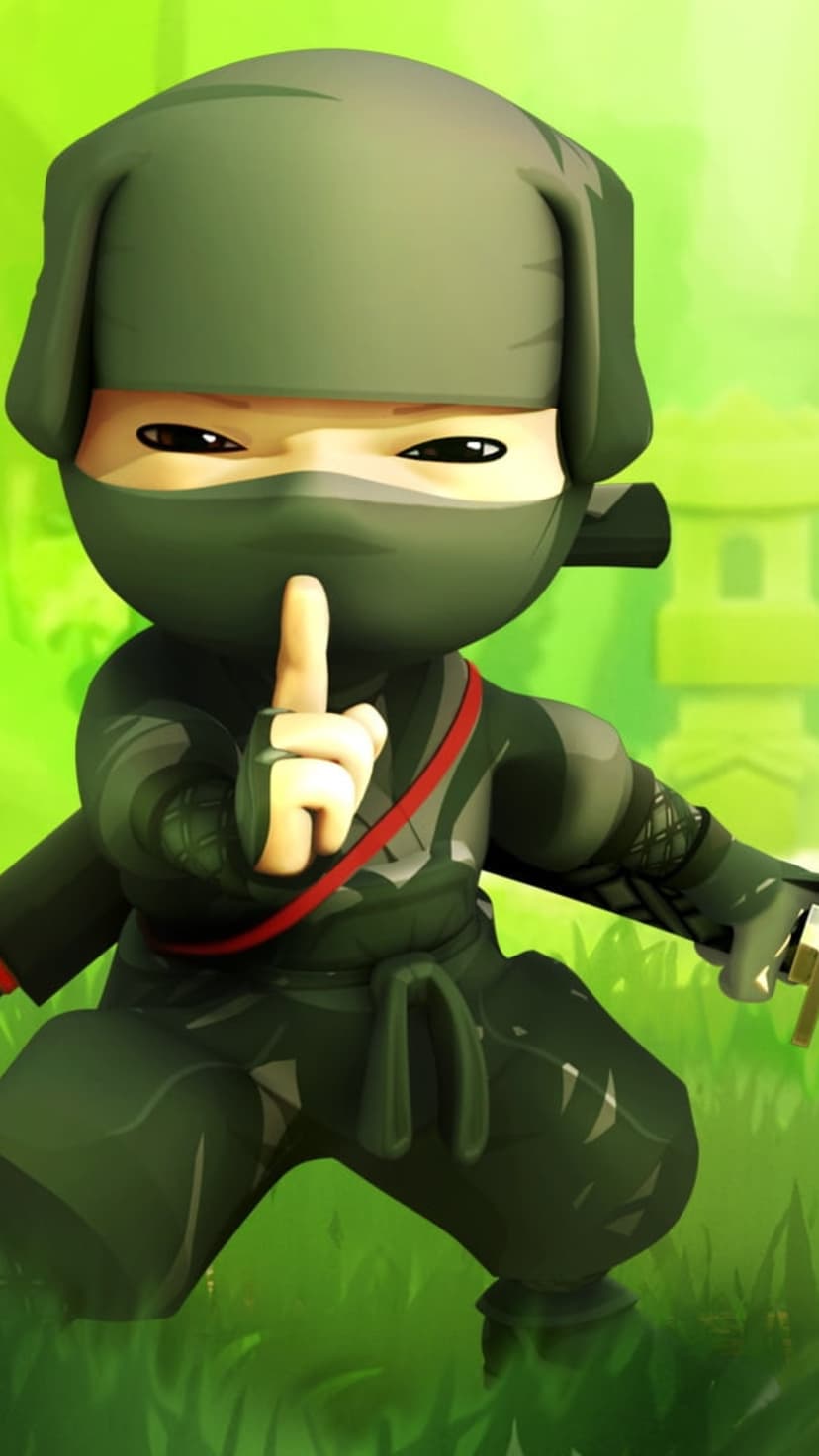 Tiny green ninja in a hood crouches on grass with a finger to its lips near a blurry Japanese stone lantern.