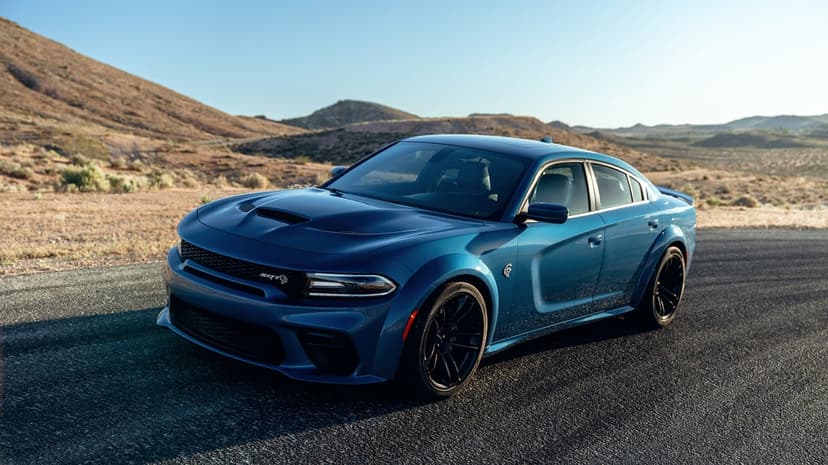 Blue Dodge Charger SRT Hellcat Widebody on an asphalt desert road against a backdrop of arid hills and clear sky.