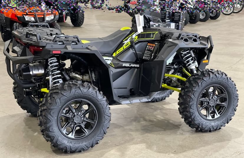 Polaris Sportsman 1000 ATV with neon yellow accents and aggressive off-road tires parked in a showroom setting.