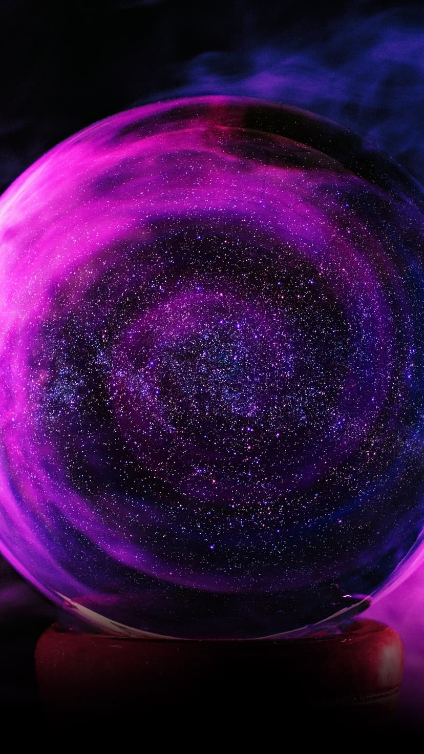 Glass orb containing a purple galaxy and stardust sits on a wooden base surrounded by wisps of white smoke.