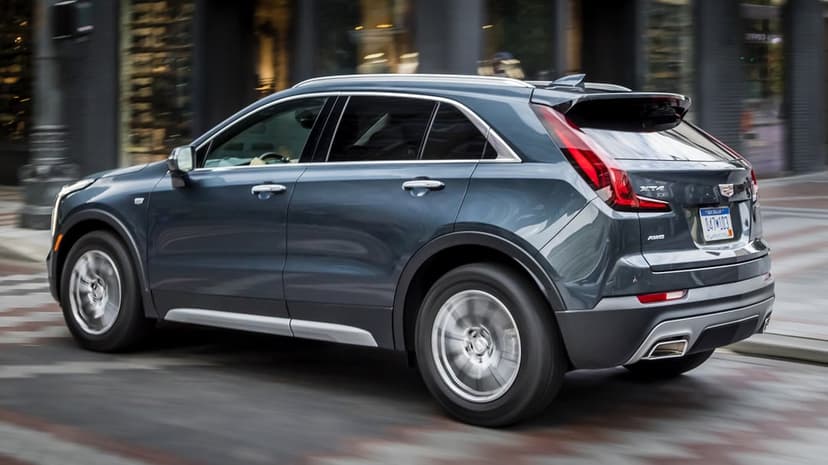 Cadillac XT4 luxury SUV driving on a city street with motion blur on wheels and blurred urban background.