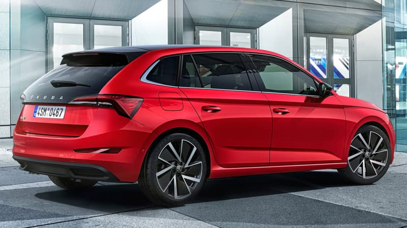 Red hatchback car with black wheels and a panoramic roof parked in front of a modern glass building.