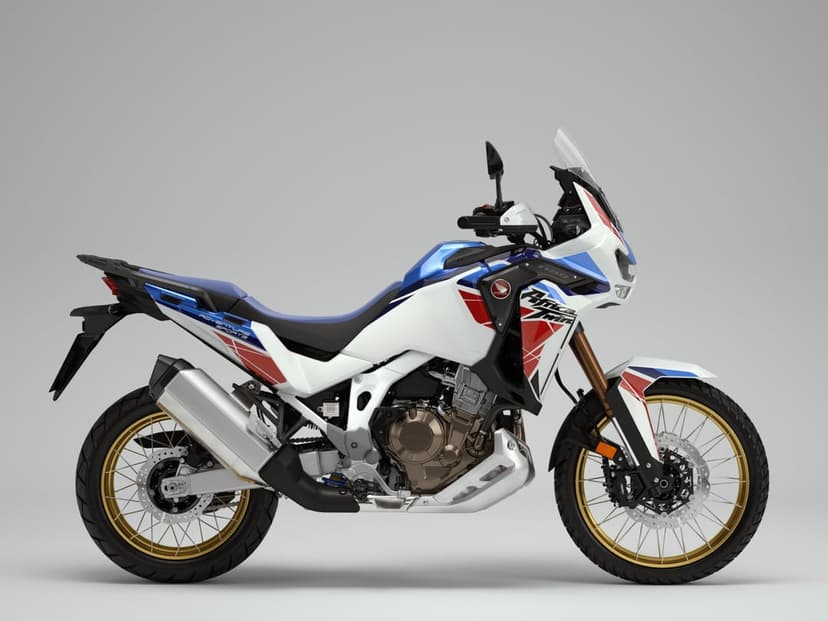 Honda Africa Twin motorcycle in tricolor white, blue, and red with gold wheels on a neutral background.