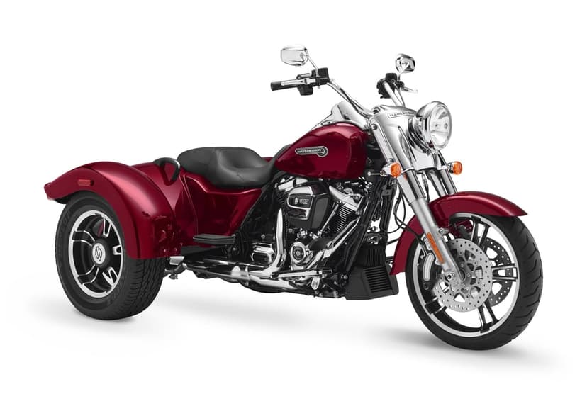 Red Harley-Davidson Freewheeler trike with chrome engine and three wheels on a minimalist white background.