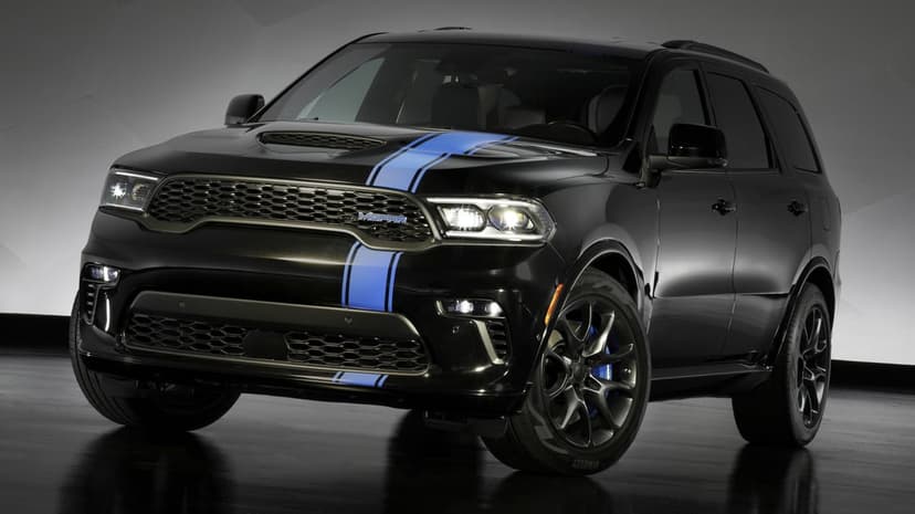 Black Dodge Durango SUV with blue racing stripes and glowing LED headlights in a dark studio setting.