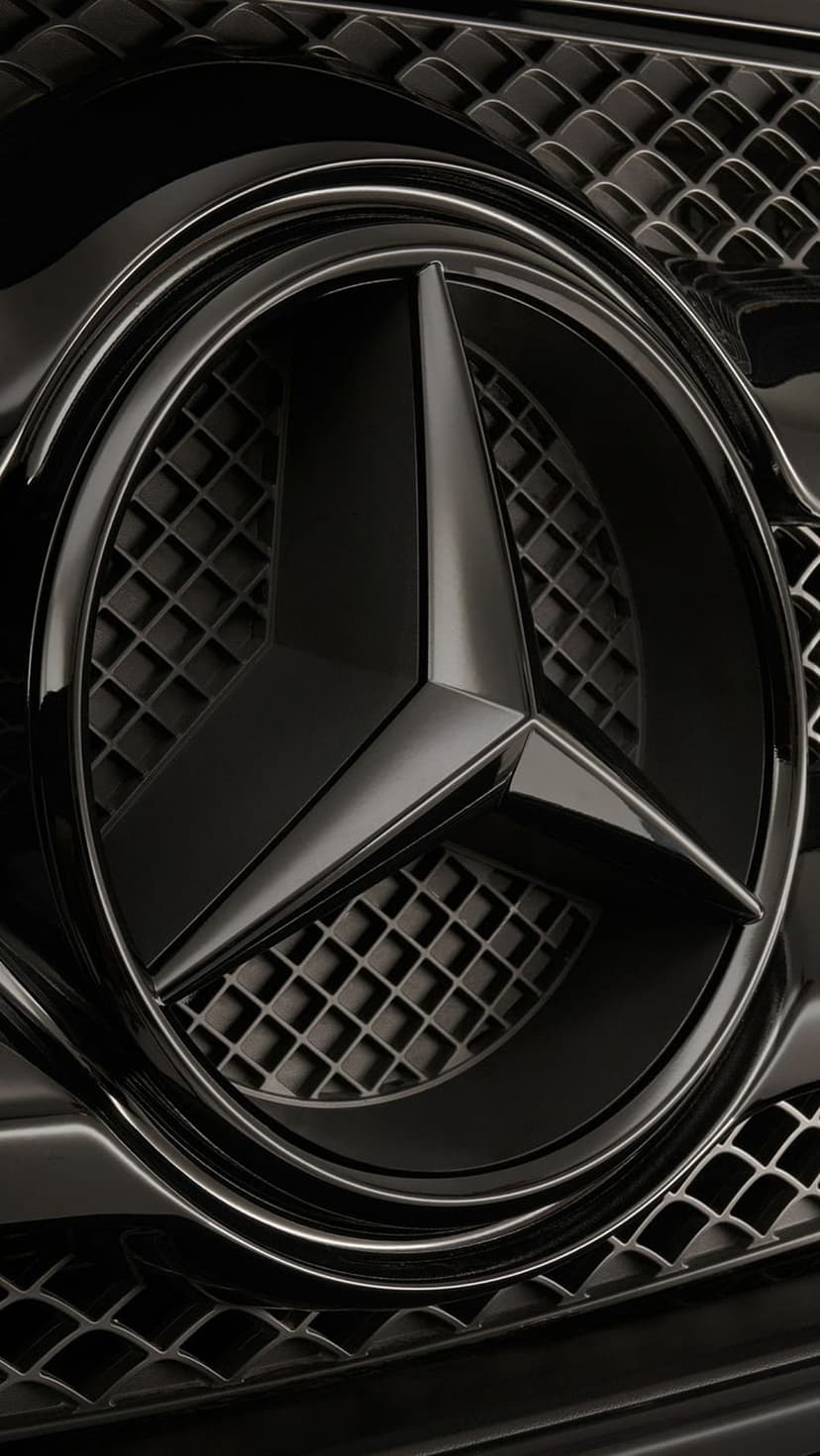 Mercedes-Benz star emblem in glossy black mounted on a matching diamond-patterned car grille in close-up.
