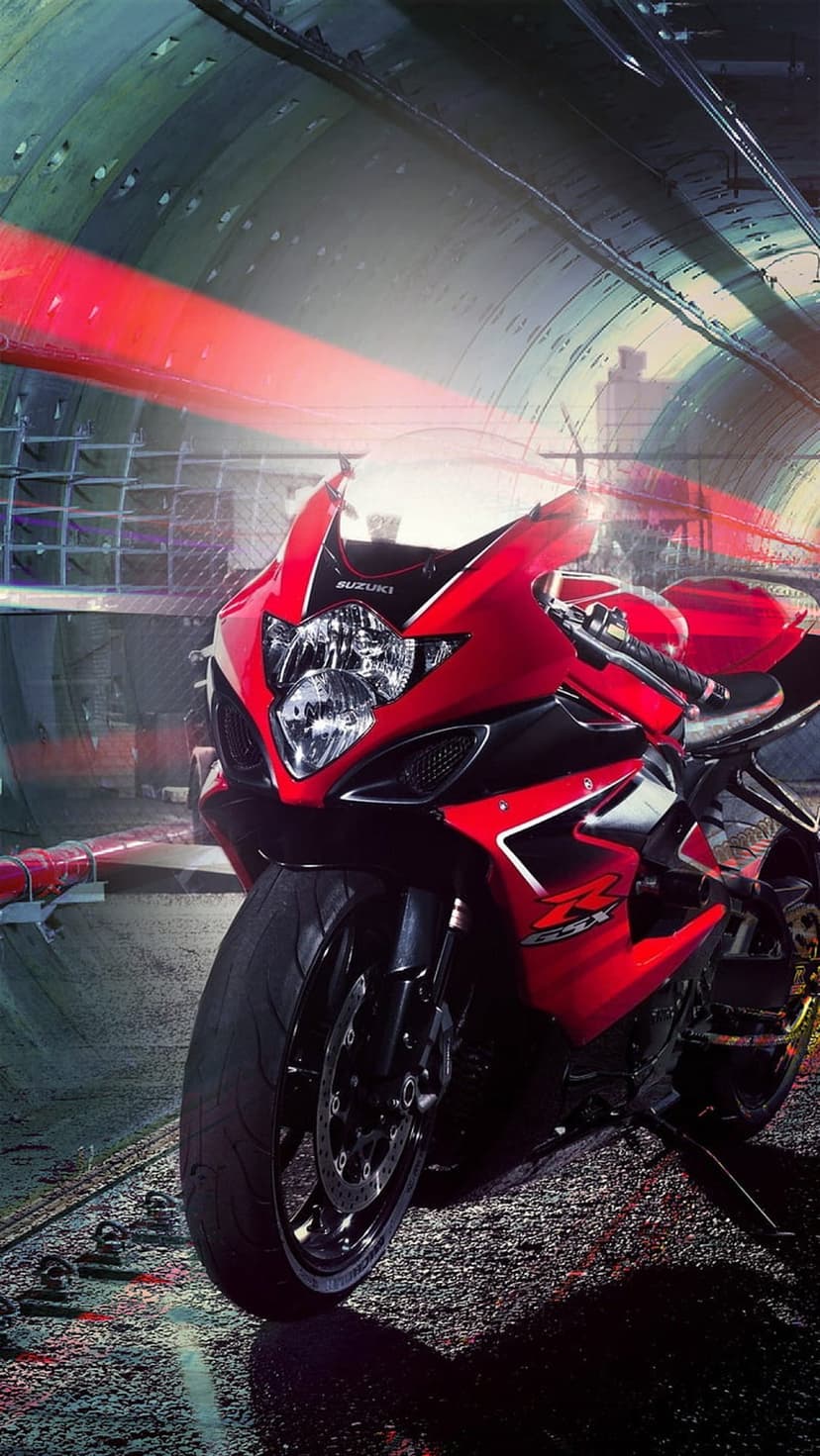 Red Suzuki GSX-R sportbike parked in a dark tunnel with vibrant red light streaks reflecting on the wet ground.