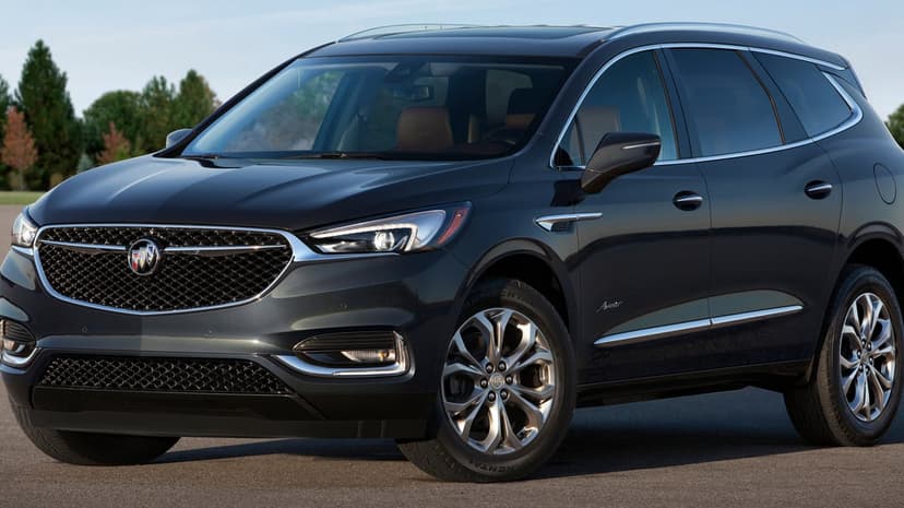Dark metallic Buick Enclave Avenir SUV parked outdoors with tan leather interior and chrome details visible.