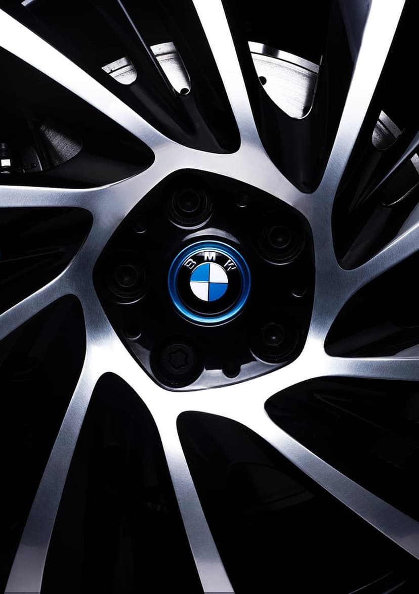 BMW emblem centered on a silver alloy wheel with metallic spokes against a dark, shadowy background.
