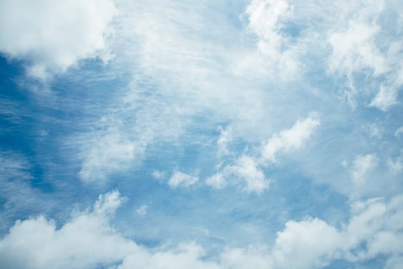 White wispy cirrus clouds and fluffy cumulus formations scattered across a bright blue daytime sky.