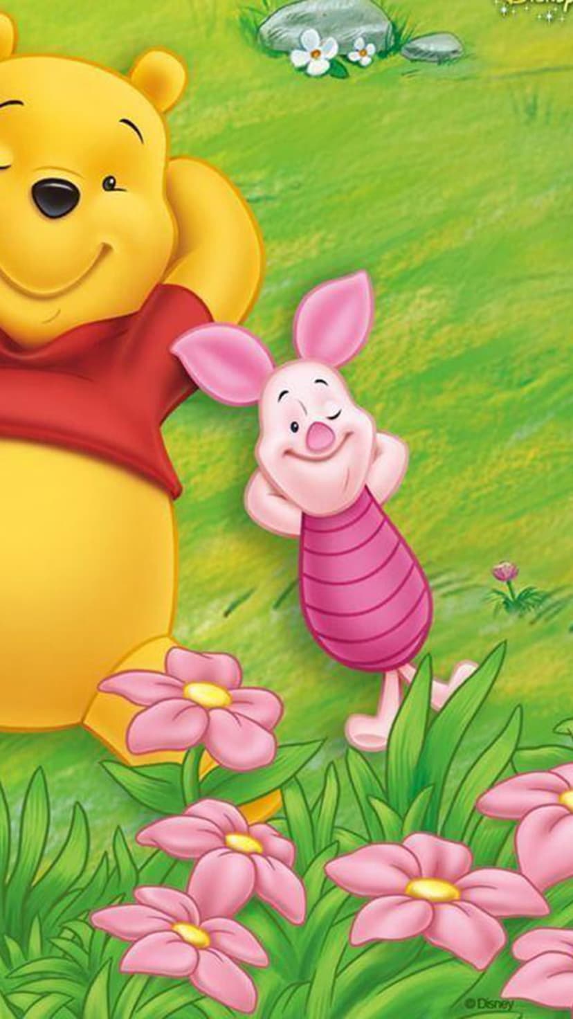 Winnie the Pooh and Piglet stand together in a lush green field filled with blooming pink flowers under a bright sky.