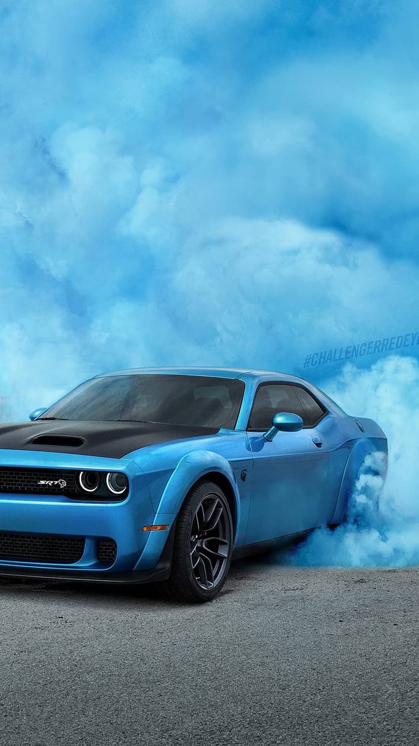 Blue Dodge Challenger SRT Demon performing a burnout with thick smoke against a clear sky in vertical orientation.