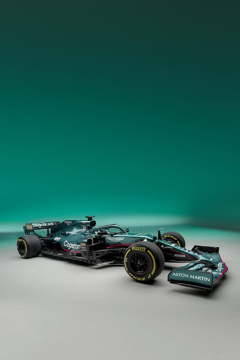 Aston Martin Formula 1 car with a green racing livery sits against a smooth teal gradient studio backdrop.