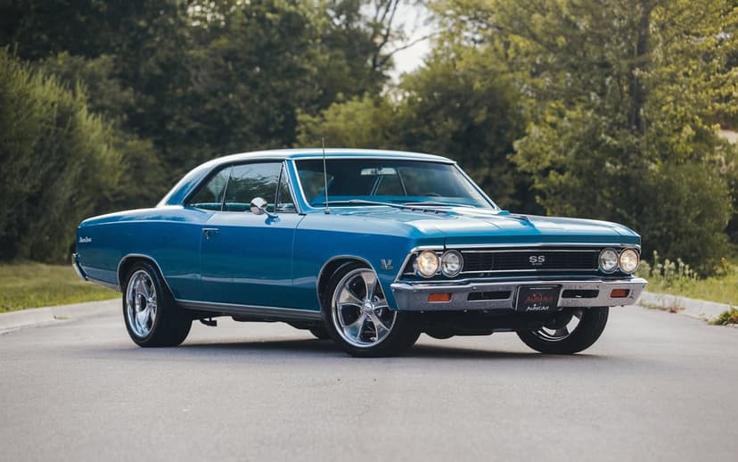 Blue vintage Chevrolet Chevelle SS 396 muscle car with chrome wheels on a paved road with trees behind.