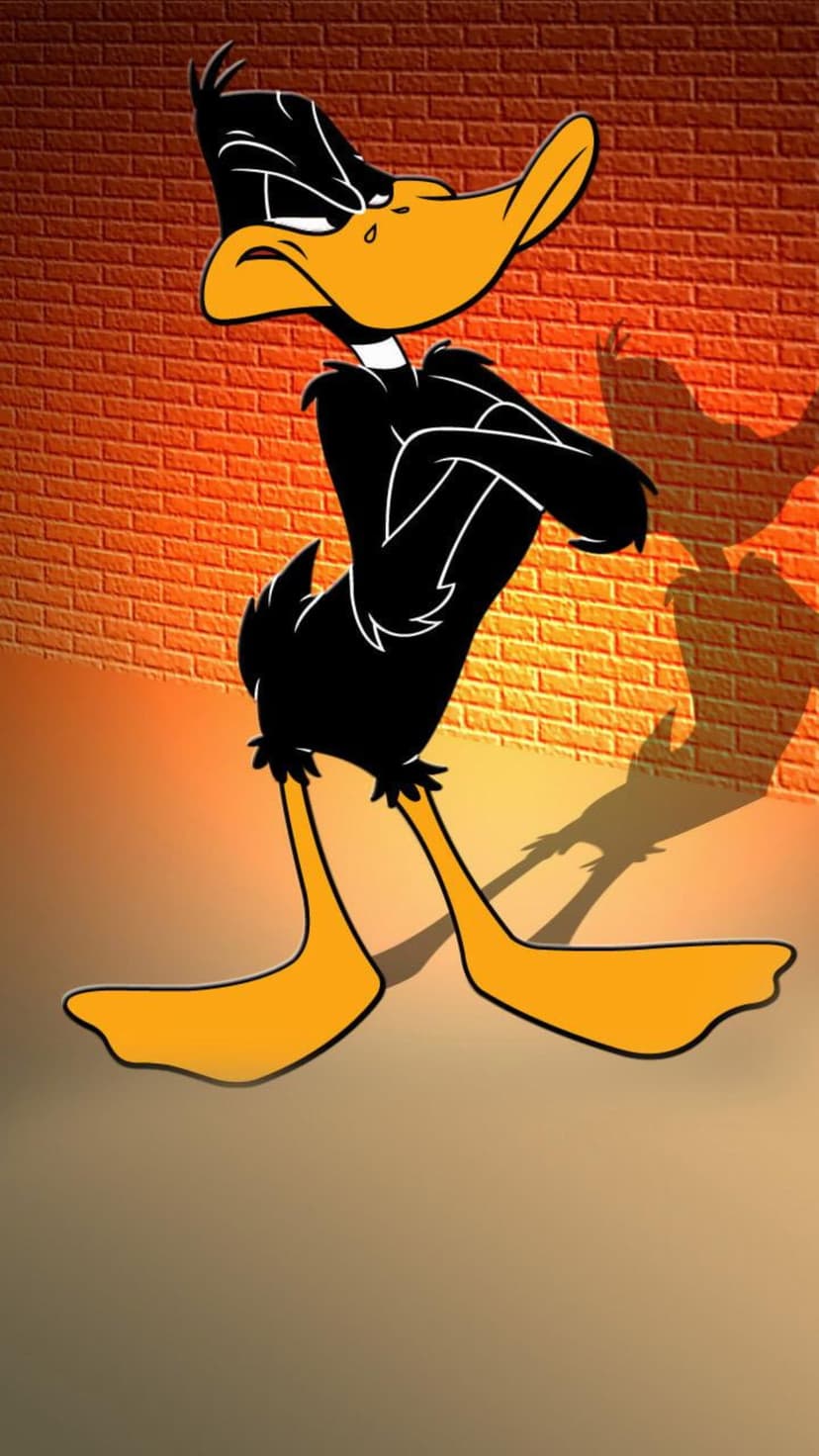 Daffy Duck stands with crossed arms against an orange brick wall, casting a long shadow on the floor.